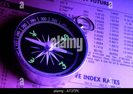 Bussola con simboli di valuta come indici giacente sul quotidiano finanziario Foto Stock