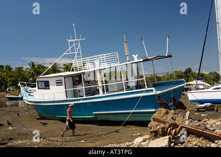 Costa Rica Quepos sport barche da pesca ormeggiato sul fiume Tagliamento a bassa marea guardato dalla Turchia avvoltoi Foto Stock