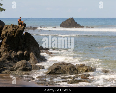 Costa Rica Osa Peninsula uomo pesca dal litorale roccioso alla foce del Rio Clara River Foto Stock