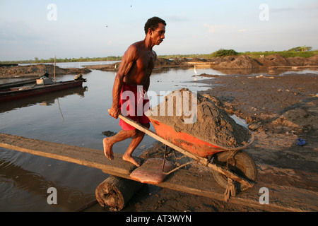 Poveri scavare sabbia dal fondo del fiume e trasportarla con canoe al litorale e venderlo agli imprenditori Foto Stock