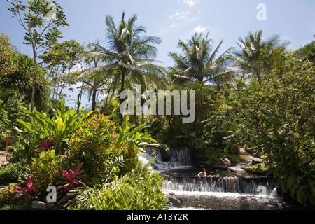 Costa Rica La Fortuna Tabacon Hot Springs Resort gli ospiti seduti in piscina tra riscaldata termicamente cascate Foto Stock