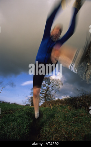 L'uomo saltando sopra un ostacolo mentre corri lungo il percorso in campagna nei pressi di Leeds Yorkshire Regno Unito Foto Stock