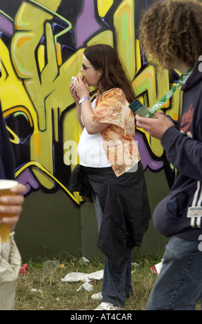 Una giovane donna di mangiare un hamburger in un concerto rock Festival Oxegen Punchestown Irlanda Foto Stock