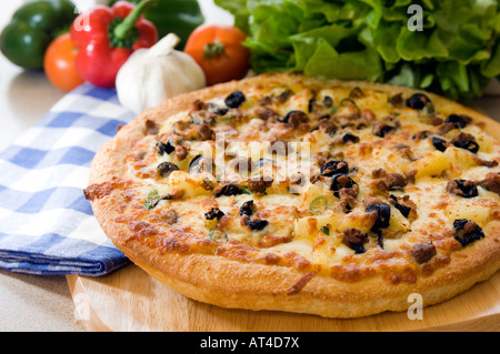 Un caldo mozzarella & olive Pizza presentato con prodotti freschi su un tagliere di legno Foto Stock