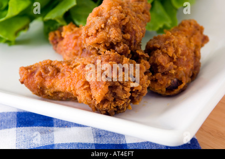 Una piastra con golden deep fried chicken wings visualizzati con una gamma di confezioni di salse Foto Stock