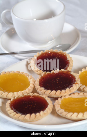 Crostate di frutta sulla piastra bianca con cucchiaio di tazza e piattino sul tavolo bianco panno Foto Stock