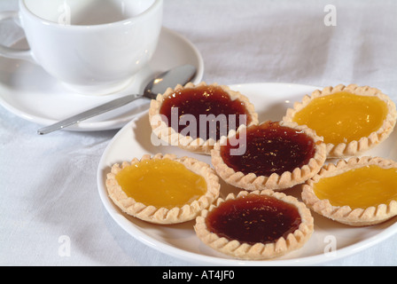 Crostate di frutta sulla piastra bianca con cucchiaio di tazza e piattino sul tavolo bianco panno Foto Stock