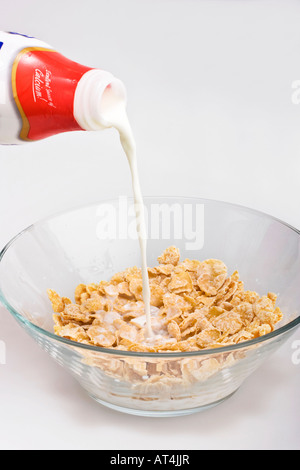 Cereali in granoturco in ciotola di vetro con latte colazione semplice per i bambini dall'alto, primo piano, sfondo bianco, formato verticale, negli Stati Uniti ad alta risoluzione Foto Stock