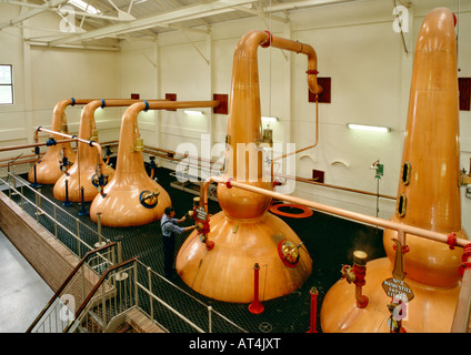 Talisker Whisky Distillery, Isola di Skye, Ebridi Interne, Scozia. L'uomo ancora controlla la pentola di rame di immagini fisse Foto Stock