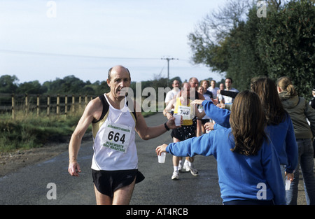 Girl Guides distribuendo acqua per guide di scorrimento in Kenilworth mezza maratona, Warwickshire, Inghilterra, Regno Unito Foto Stock