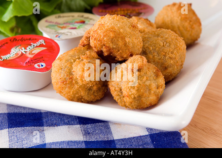 Una piastra di golden fritte funghi impanati visualizzata con una gamma di confezioni di salse Foto Stock