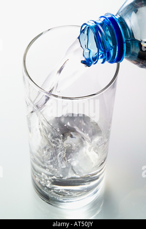 Acqua minerale versata in un bicchiere vuoto da una bottiglia Foto Stock