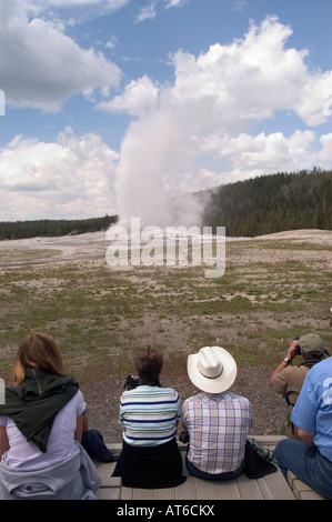 I visitatori osservano geyser Old Faithful eruttano presso il Parco Nazionale di Yellowstone, WY. Foto Stock