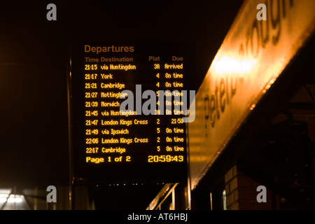 Stazione ferroviaria scheda di partenza sulla piattaforma della stazione a tarda notte Foto Stock