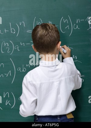 Ragazzo (10-11) di scrivere sulla lavagna, vista posteriore Foto Stock