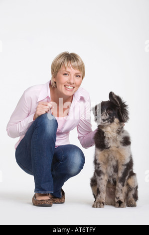 Giovane donna accovacciata dal cane, ritratto Foto Stock
