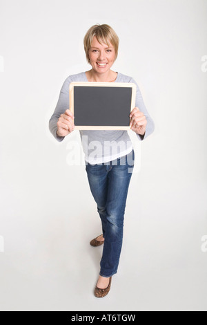 Giovane donna holding blackboard, sorridente, ritratto Foto Stock