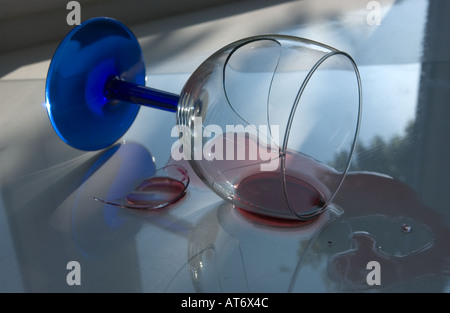 Un blu wineglass con gambo rotto e versare i resti di un bicchiere di vino rosso Foto Stock