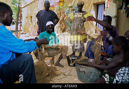Pescatori della tribù Bozo che districano pesci da una rete nel villaggio di Dagua Womina sul fiume Niger, Mali Foto Stock