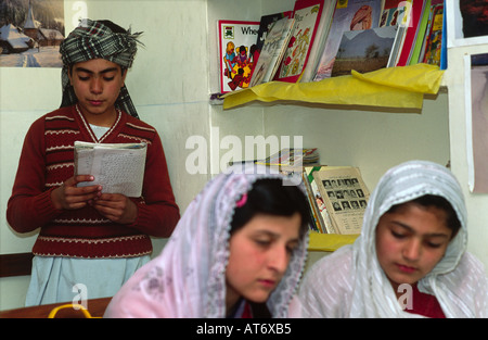 Scolaro musulmano la lettura ad alta voce mentre i compagni di scuola femminile ascoltare, presso il British modello di scuola a Quetta, in Pakistan Foto Stock