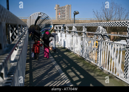 Una famiglia a piedi su un ponte a ovest di Londra, si affaccia il Goldfinger-costruito a torre, Trellick Tower Foto Stock