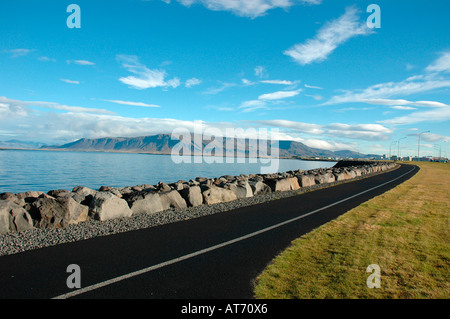 Pista ciclabile lungo la costa con rocce e massi nella città di Reykjavik Islanda Foto Stock