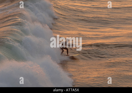Surfer cattura un'onda nell'incandescenza di un California Sunset Foto Stock