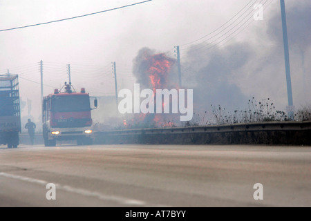 Grecia quattro settimane dopo la incendi. auto dei vigili del fuoco su una strada nazionale che è completamente coperto di fumo e di fiamme Foto Stock