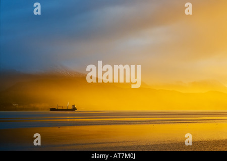 Spettacolare alba su incandescente foschia mattutina nel porto di Ushuaia Sud dell Argentina con la nave da carico a distanza Foto Stock