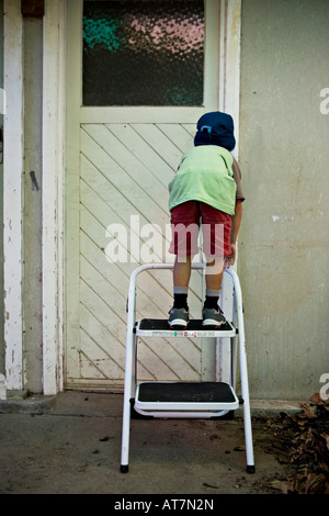 Ragazzo guarda attraverso il buco della serratura Foto Stock