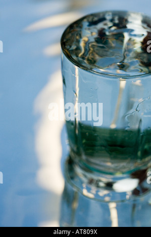 Versare acqua in un bicchiere che si erge su uno specchio Foto Stock