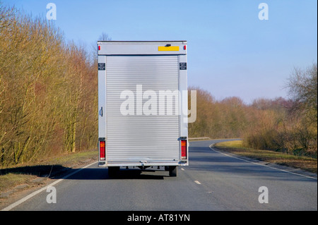 Consegna van con una tapparella indietro la guida su una strada durante una soleggiata giornata autunnale Foto Stock