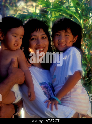 Un Portoghese madre hawaiana sorrisi come lei tiene i suoi due figli. Foto Stock