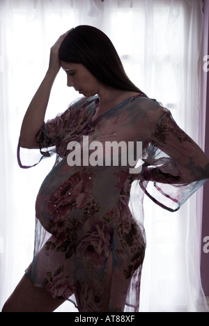 Donna incinta in capo a strapiombo sorge da una finestra testa in mano Foto Stock