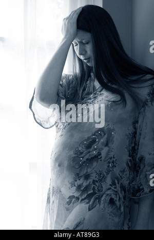 Donna incinta in capo a strapiombo sorge da una finestra tenendo la testa Foto Stock