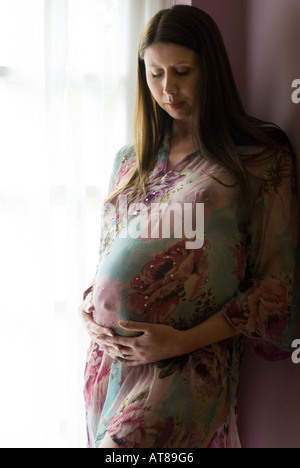 Donna incinta in capo a strapiombo sorge da una finestra Foto Stock