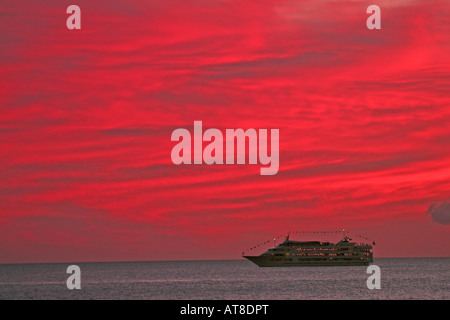 La nave di crociera con colore rosso brillante nuvole dal tramonto off Honolulu. Foto Stock