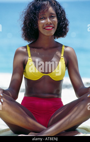 Giovane donna seduta sulla spiaggia tropicale Foto Stock
