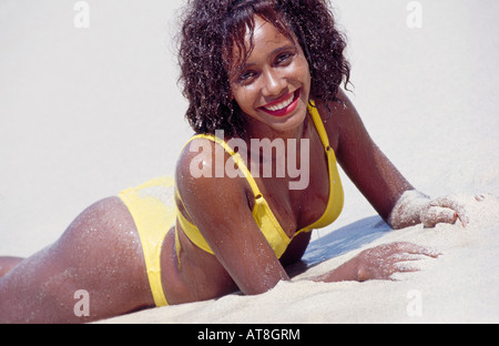 Giovane donna sdraiata sulla spiaggia sabbiosa Foto Stock