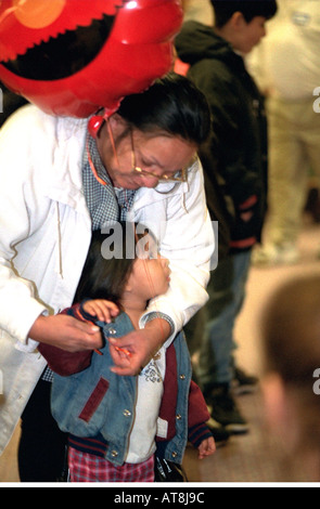 Mamma e figlia età 35 e 4 di legatura a palloncino soup kitchen cena di ringraziamento. Minneapolis Minnesota USA Foto Stock