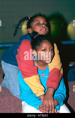 Nero Ragazza dando la sorella di un caldo abbraccio età 7 e 12. La gioventù Express dopo la scuola programma di studio St Paul Minnesota USA Foto Stock