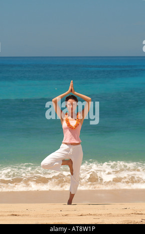 Giovane donna fare yoga sulla spiaggia Foto Stock