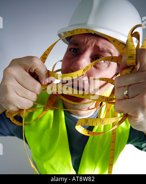 Lavoratore edile con un intricato nastro di misurazione Foto Stock