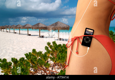 Donna con iPod nano nascosto in rosso cintura bikini in ambiente tropicale Foto Stock