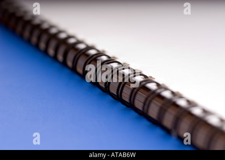 Macro di un bianco anello a spirale documento rilegato su uno sfondo blu Foto Stock