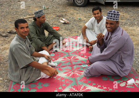 Quattro uomini carte da gioco nel deserto da strada Oman Foto Stock