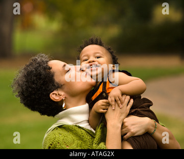 Testa e la spalla ritratto di donna holding e baciare Ragazzo come egli sorride Foto Stock