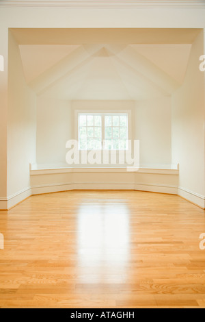 Stanza vuota in casa con la luce del sole proveniente attraverso la finestra su pavimenti in legno duro Foto Stock