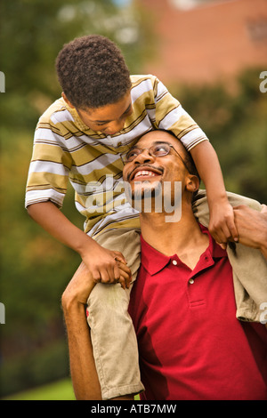 Padre che porta il suo figlio sulle sue spalle sorridente e guardando a vicenda Foto Stock