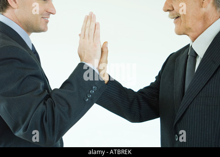Due imprenditori dando a ogni altro ad alta cinque, ritagliato vista laterale Foto Stock